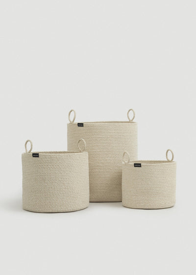 Three beige cotton rope baskets in graduated sizes arranged together.