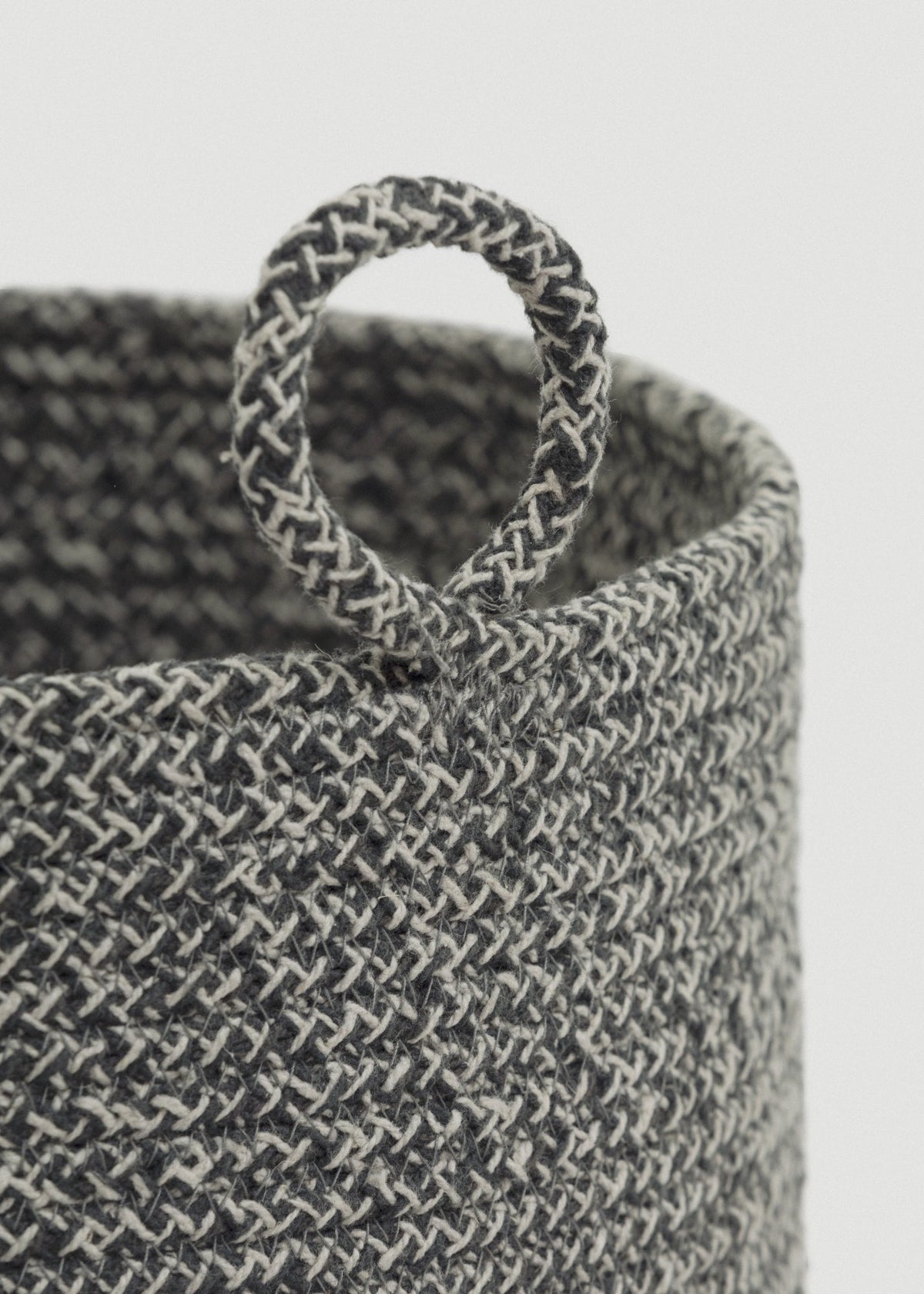 Close-up of the gray-and-cream braided rope, rounded rim, and circular loop handle.