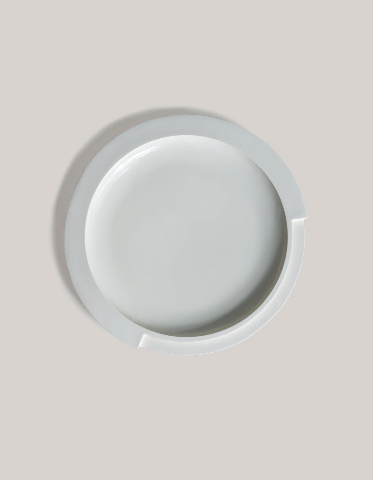 Tortuga Forma Kaolin Platter White viewed directly from above on a light grey background, showing its smooth circular centre, broad raised rim and two offset notches along the edge.
