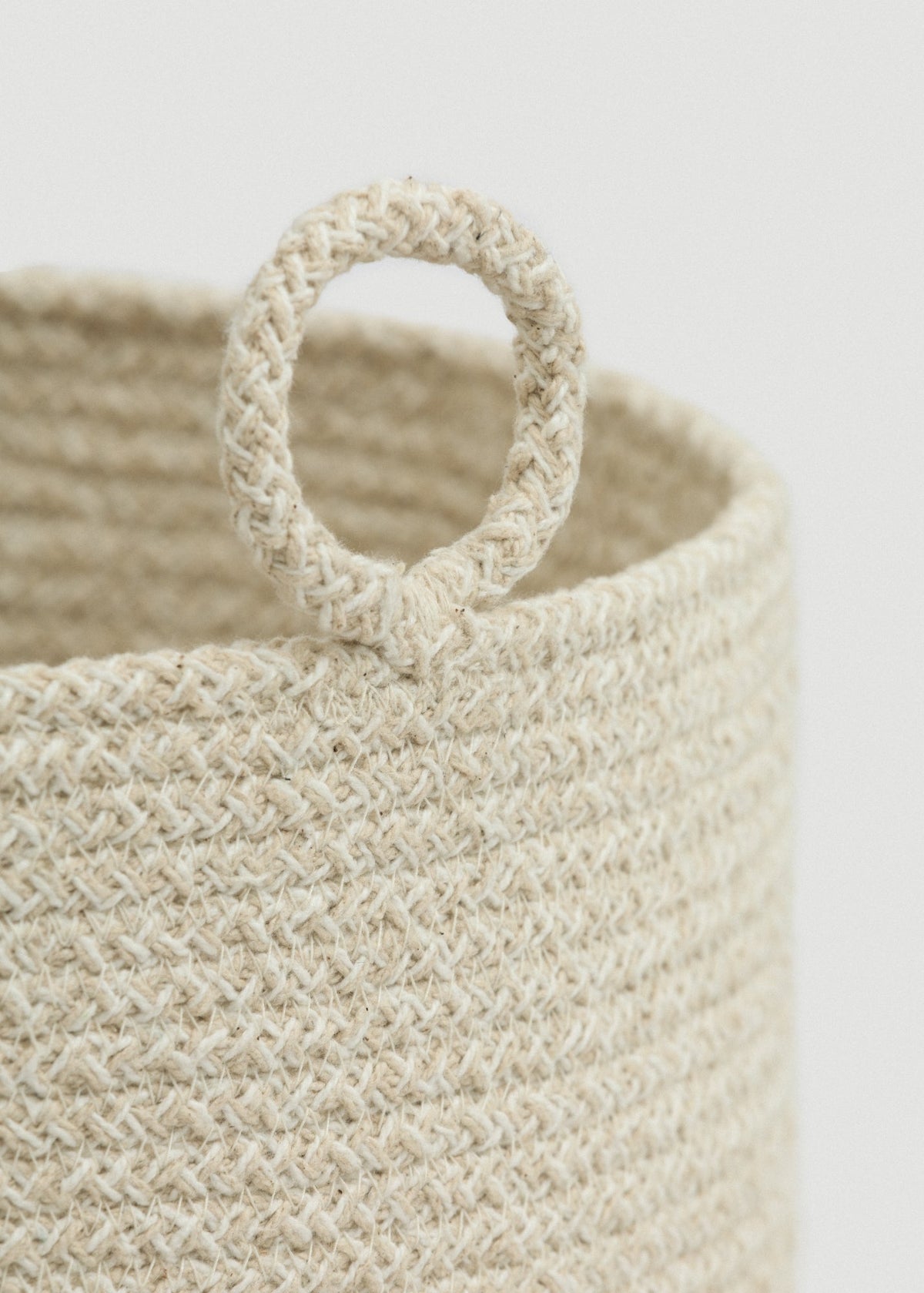 Close-up of the cream-and-beige braided rope, rounded rim, and circular loop handle.