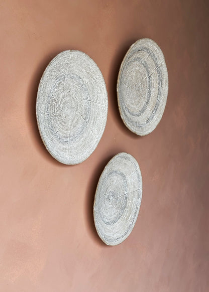 Three round textured wall decor pieces on a brown background