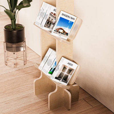 Close angled view of magazines displayed on the lower shelves of the Yankel natural wood bookcase beside a potted plant