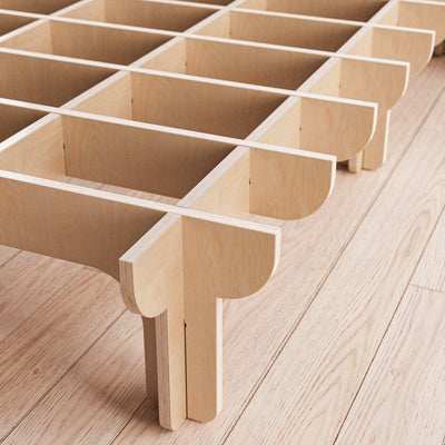 Close-up of the DOVID bed frame’s unfinished natural wood support system, showing interlocking slats, rounded joints and multiple legs