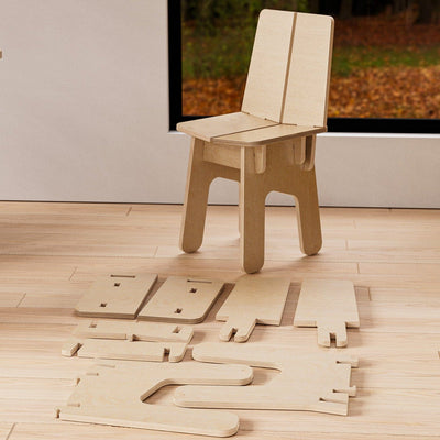 Assembled BURIJ natural wood chair displayed behind its precisely cut flat-pack components arranged across the floor