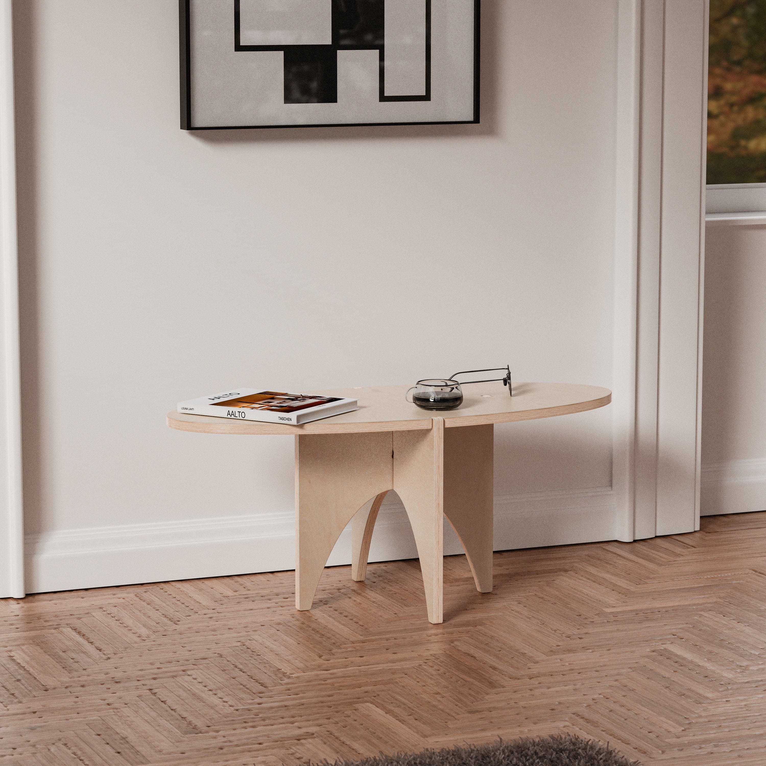 YOYO natural wood accent table against a white wall, styled with magazines and small accessories beneath framed geometric artwork