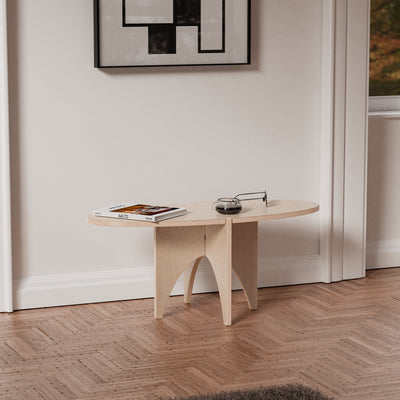 YOYO natural wood accent table against a white wall, styled with magazines and small accessories beneath framed geometric artwork