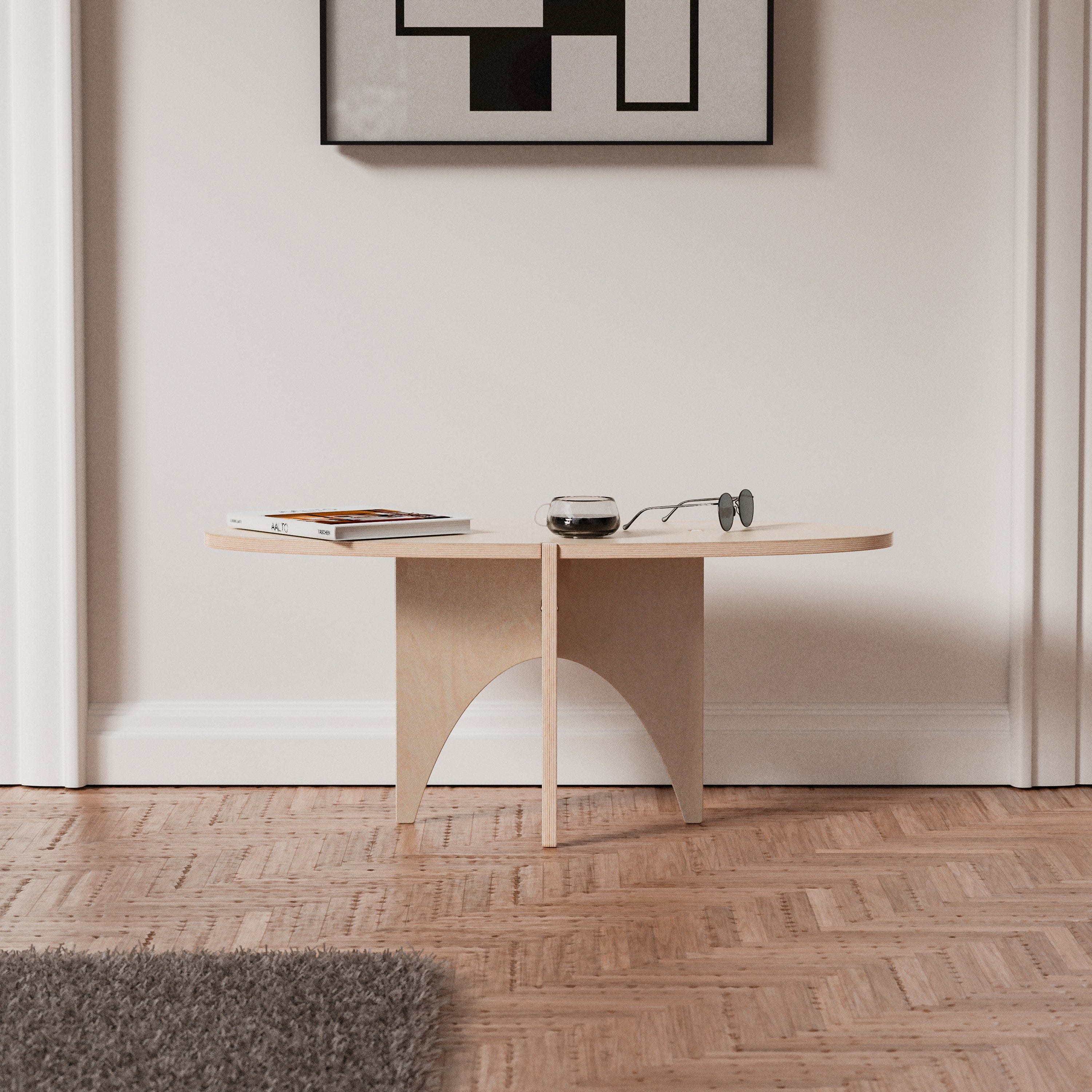 Front view of the YOYO natural wood accent table with its slim oval top and sculptural intersecting legs, styled beneath framed artwork