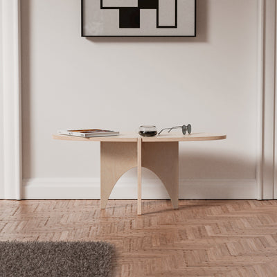 Front view of the YOYO natural wood accent table with its slim oval top and sculptural intersecting legs, styled beneath framed artwork