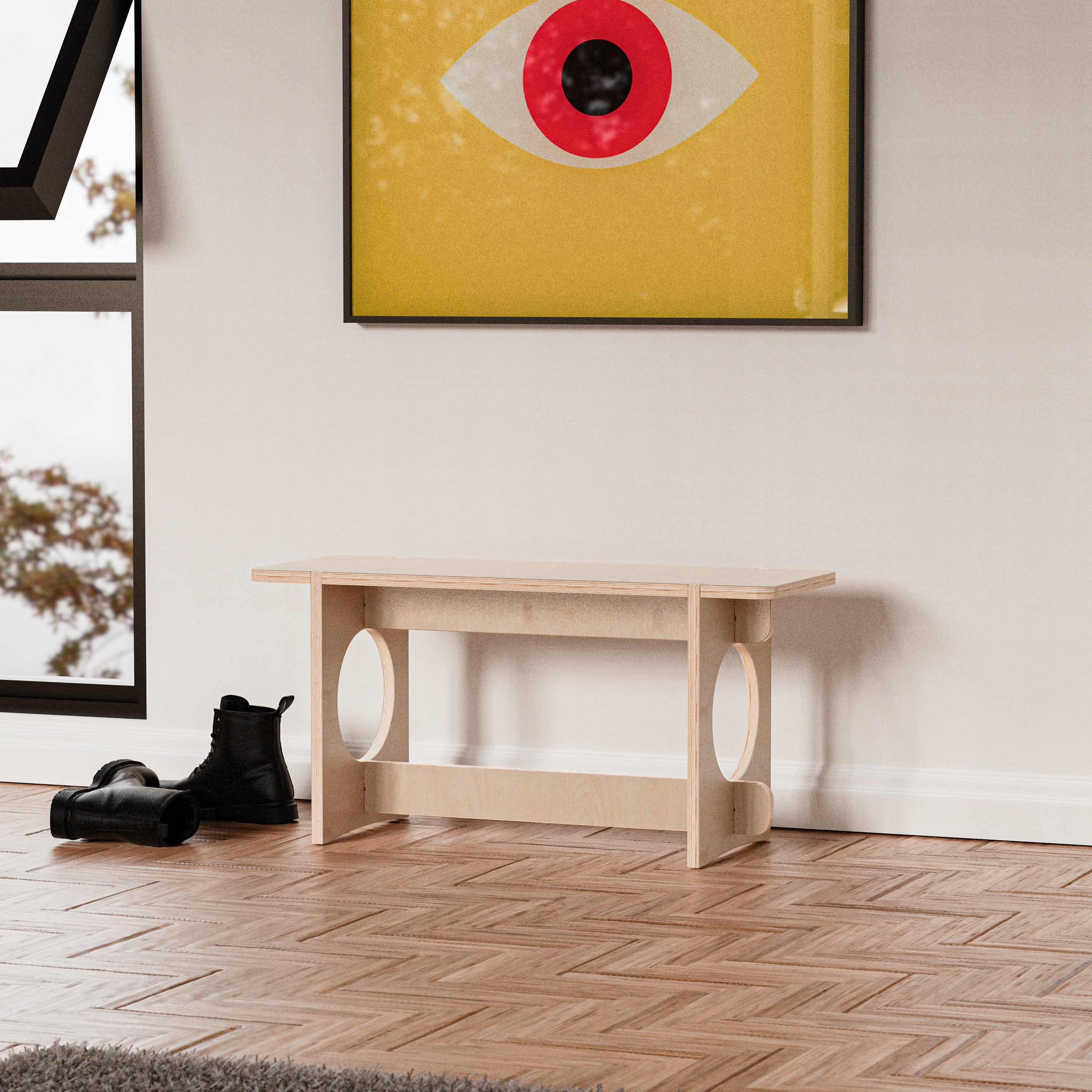 Front view of the YOYO wood bench styled beneath colorful geometric artwork, with black boots nearby on a herringbone floor