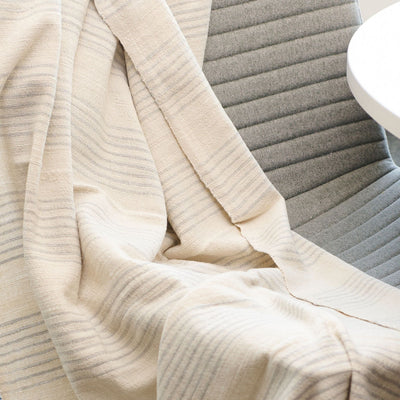 Silica Chalk off-white and gray striped throw gathered across a gray chair, highlighting its lightweight, fluid drape