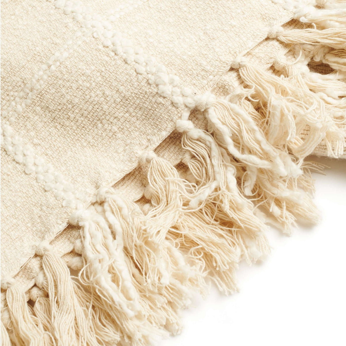 Extreme close-up of the Sea Shell White throw’s thick woven texture, raised checks and loosely knotted cream fringe