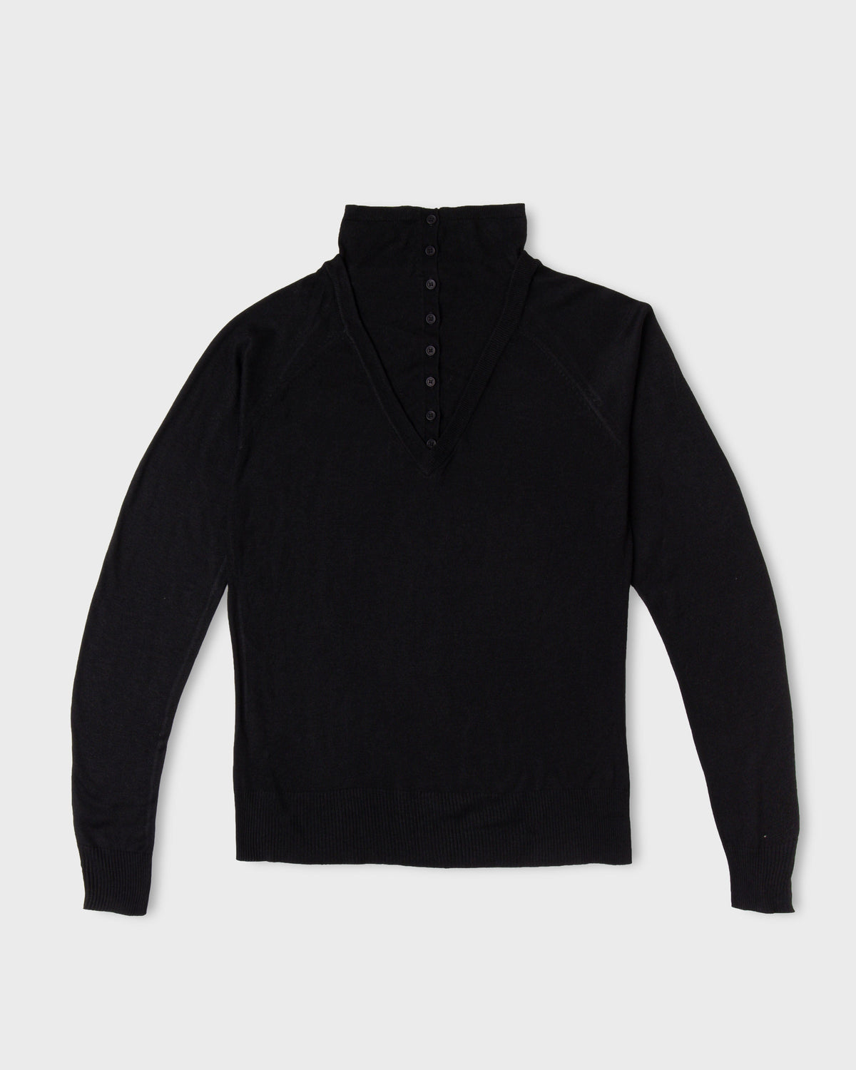 Black Paulette Montagne Top displayed against a light background, with a tall collar, short tonal button placket, subtle shoulder gathers, long sleeves, and a straight hem.