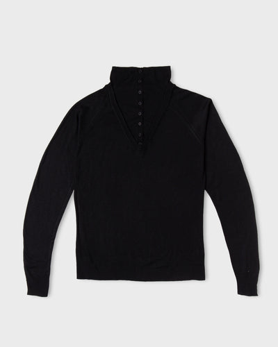 Black Paulette Montagne Top displayed against a light background, with a tall collar, short tonal button placket, subtle shoulder gathers, long sleeves, and a straight hem.
