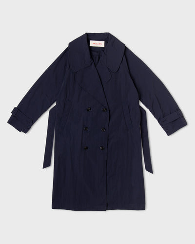 Dark navy Paulette Louise Trench Coat displayed against a light background, showing a broad rounded collar, oversized overlapping lapels, six dark buttons in two rows, slanted pockets, cuff straps, and a matching belt hanging at the sides.