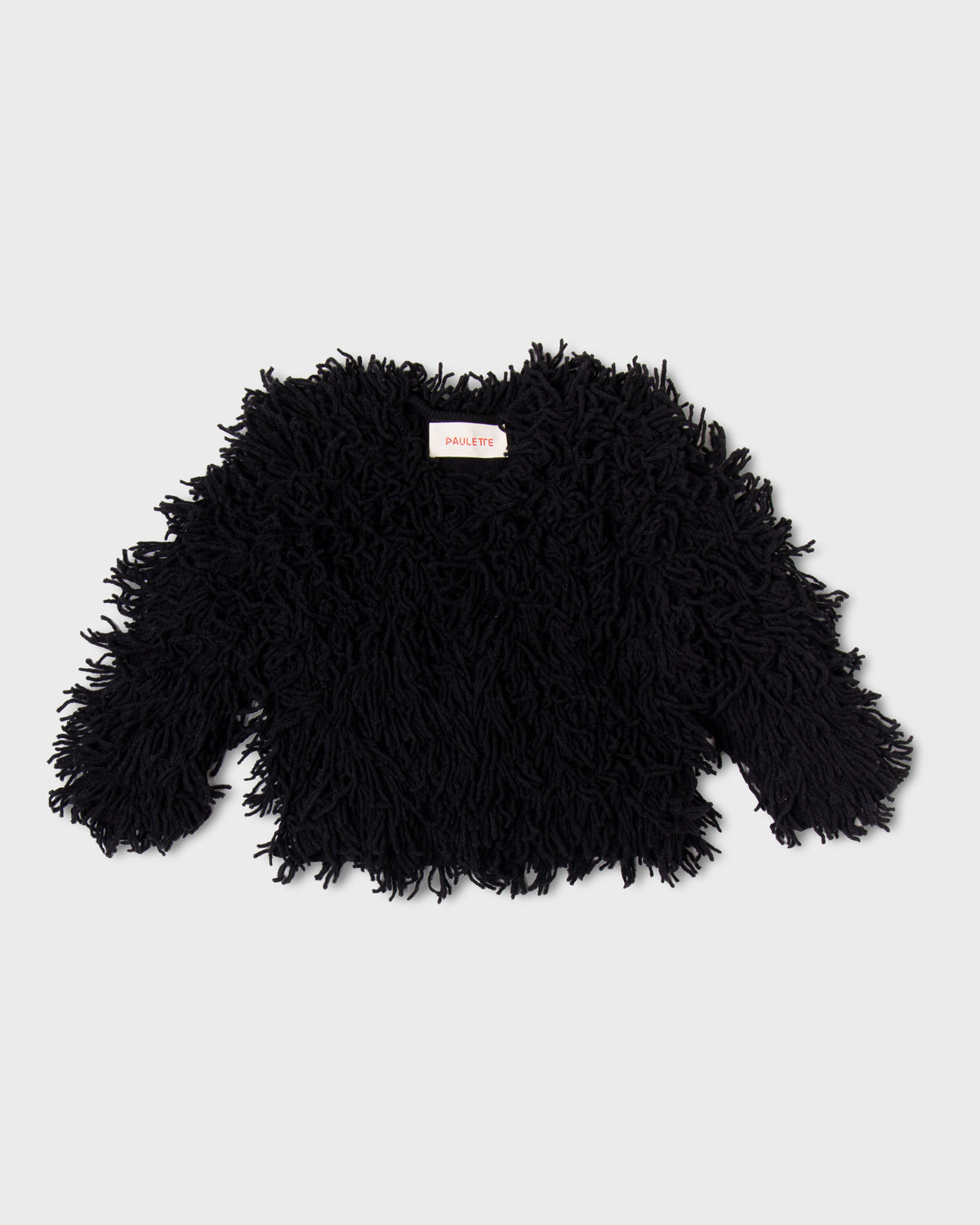Black Paulette Saint-Jean-de-Luz Cardigan displayed against a light gray background, showing a short, wide body, long sleeves, and dense shaggy strands covering the neckline, cuffs, and hem.