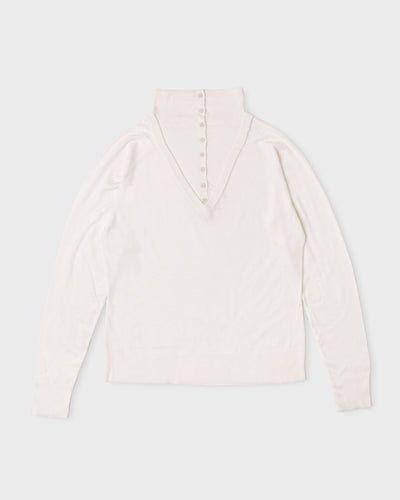 Ivory Paulette Montagne Top displayed against a light background, showing a tall collar, small buttons along a tapered front placket, softly gathered shoulders, long sleeves, and a straight hem.