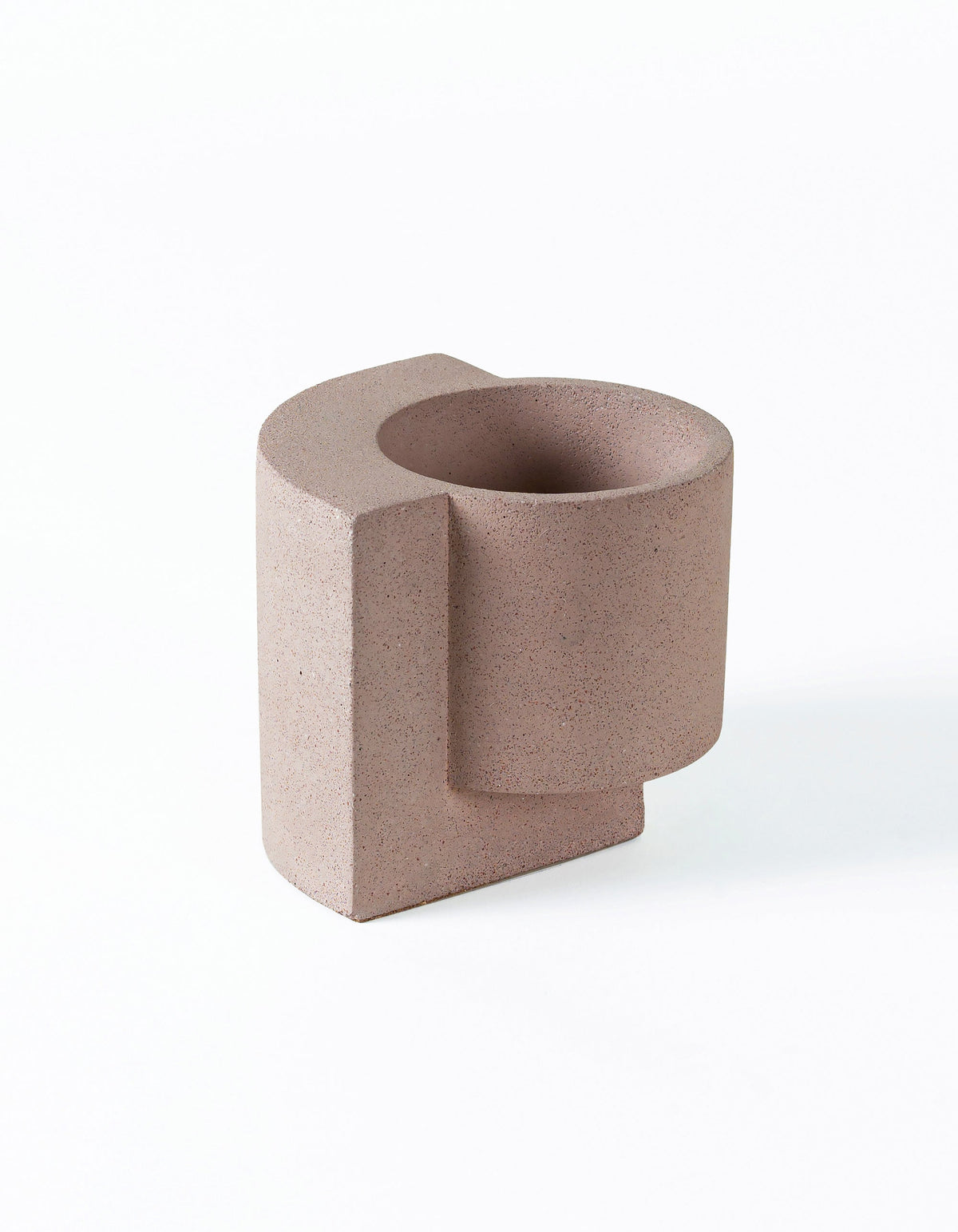 Coral Tortuga Forma Platform Planter Small - Terrazzo viewed at an angle on white, showing a round planting cavity and cylindrical pot joined to a flat vertical slab that extends beneath it, with fine dark speckles throughout.