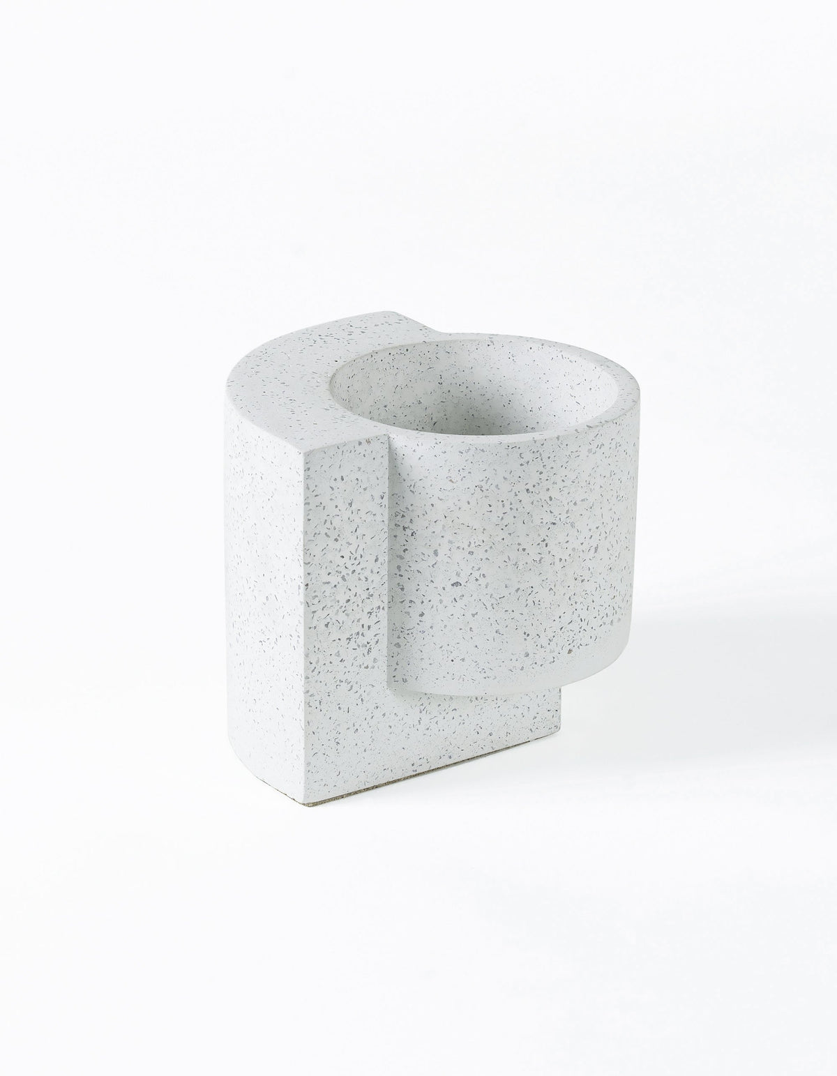 White Tortuga Forma Platform Planter Small - Terrazzo viewed at an angle on white, showing grey speckles, a deep round planting cavity and a flat slab extending along one side and beneath the cylindrical pot.