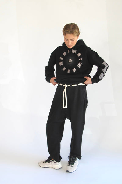 Model wearing black cotton-fleece Picasso pants with a long white drawstring, black graphic sweatshirt, and white sneakers.