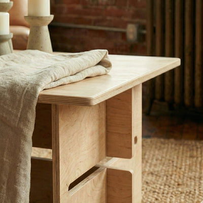 Close-up of the Williamsburg coffee table showing its pale wood top, layered plywood edge and interlocking panel construction
