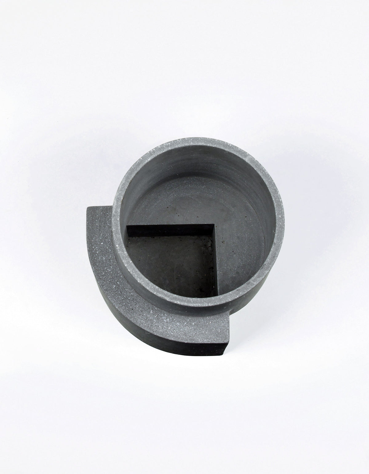 Overhead view of the graphite Tortuga Forma Platform Planter Medium Terrazzo, revealing its thick circular rim, empty interior and angular raised section within the bottom.