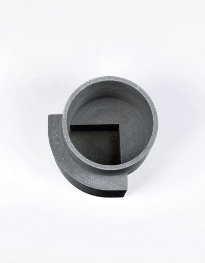 Overhead view of the graphite Tortuga Forma Platform Planter Medium Terrazzo, revealing its thick circular rim, empty interior and angular raised section within the bottom.