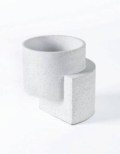 White Tortuga Forma Platform Planter Medium Terrazzo viewed at an angle on white, showing fine grey flecks, an open cylindrical bowl and an offset slab support with a curved outer edge.