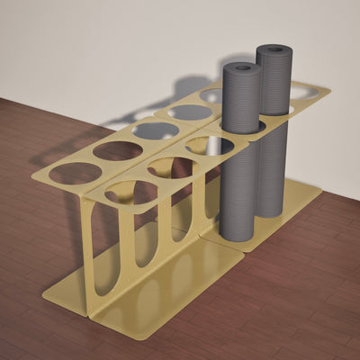Gold floor stand holding four gray rolled mats or foam rollers, showing the long rectangular base and open storage slots.