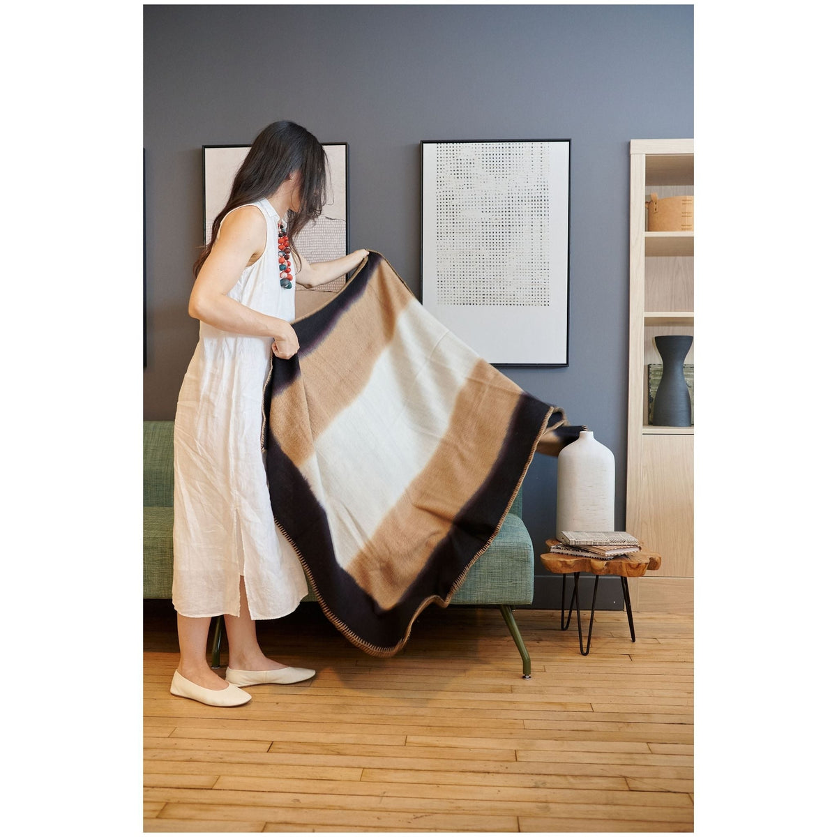 Woman standing and holding the Siro Brown throw open to display its full size, cream center and dark borders