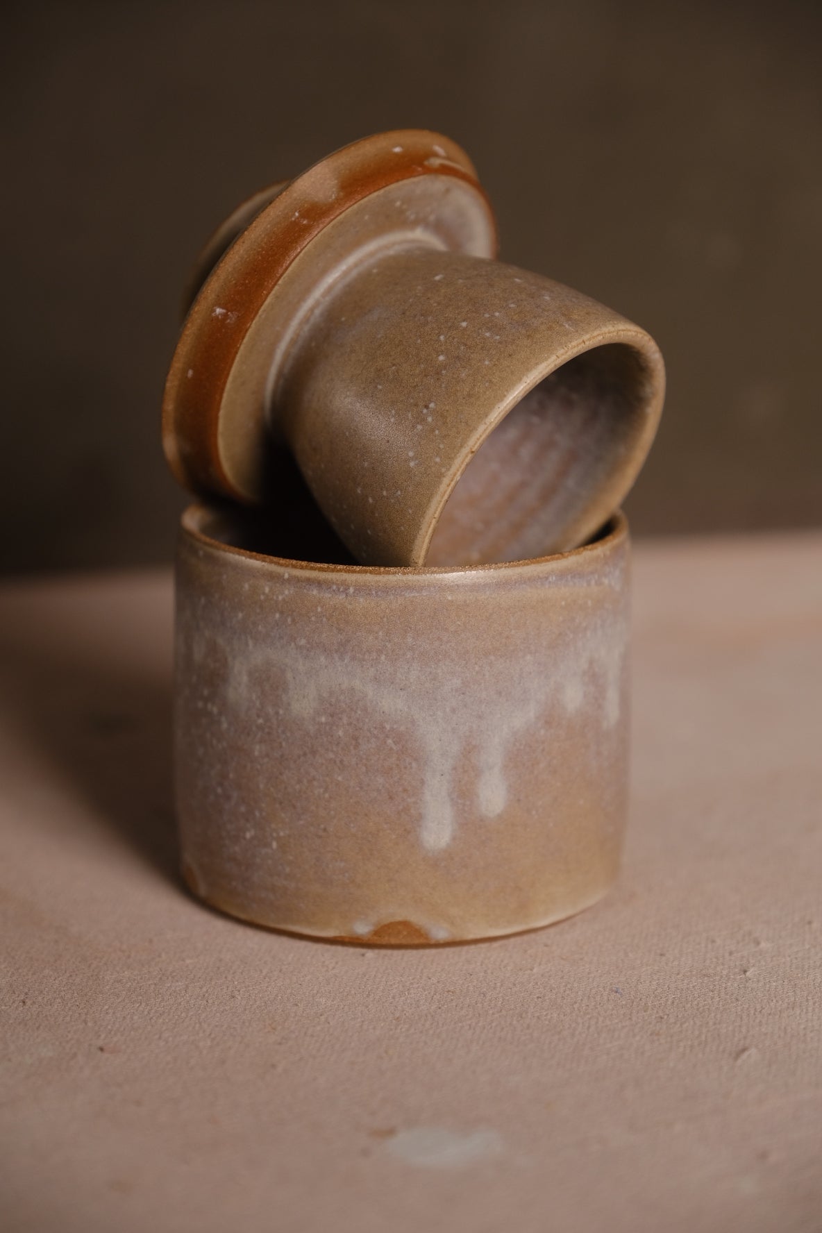 Beige Settle Ceramics Butterbell with pale glaze streaks running down the base, its lid tipped back to reveal the speckled interior of the attached cup.