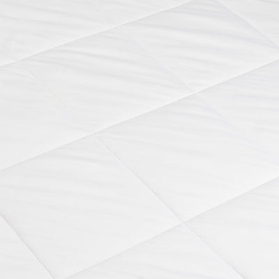 Close-up of the white comforter’s smooth fabric and intersecting diagonal stitching, forming large quilted sections.