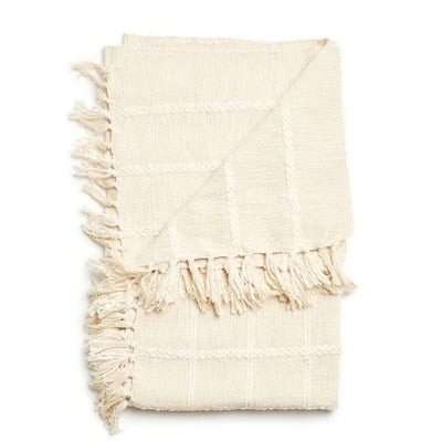 Folded Sea Shell White handloom throw with its raised check pattern and knotted fringe layered across the center