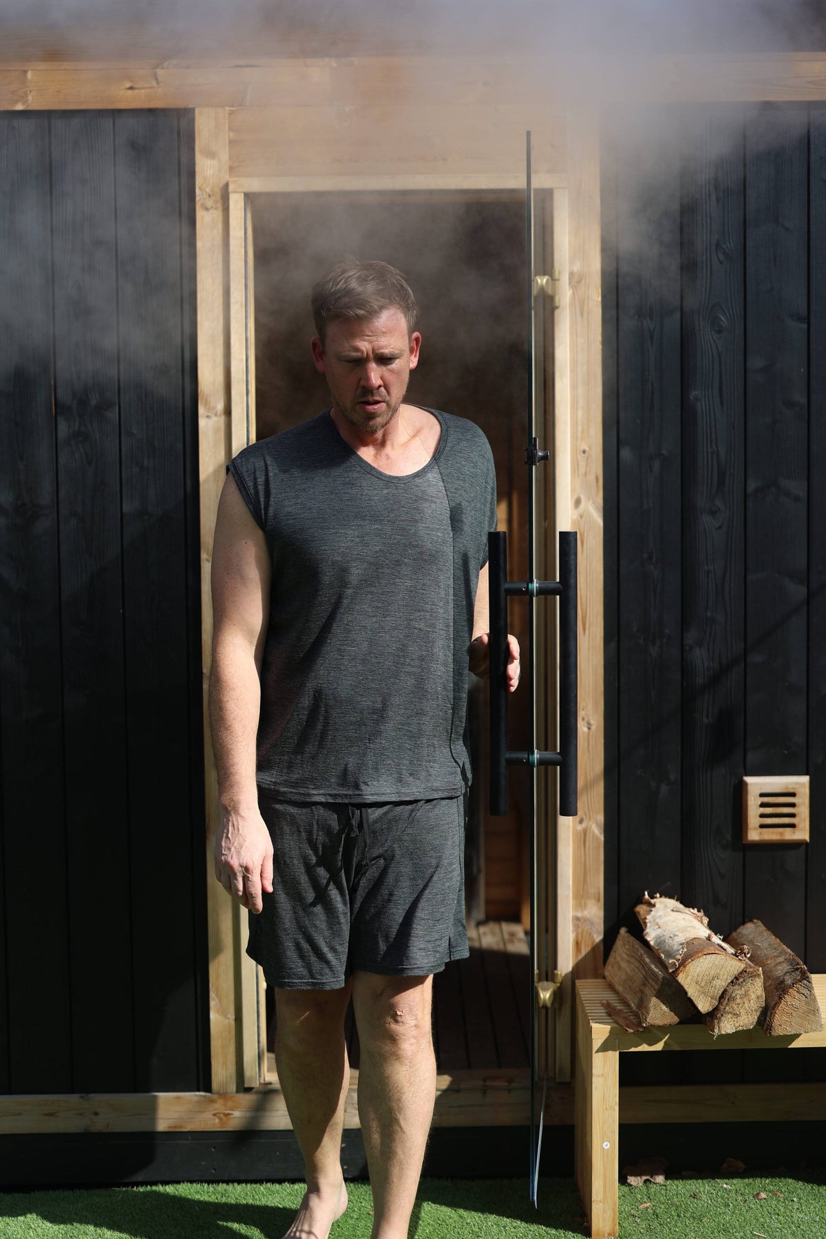 Men's merino wool sauna shorts worn outdoors near sauna entrance, showcasing lightweight natural wool performance apparel.