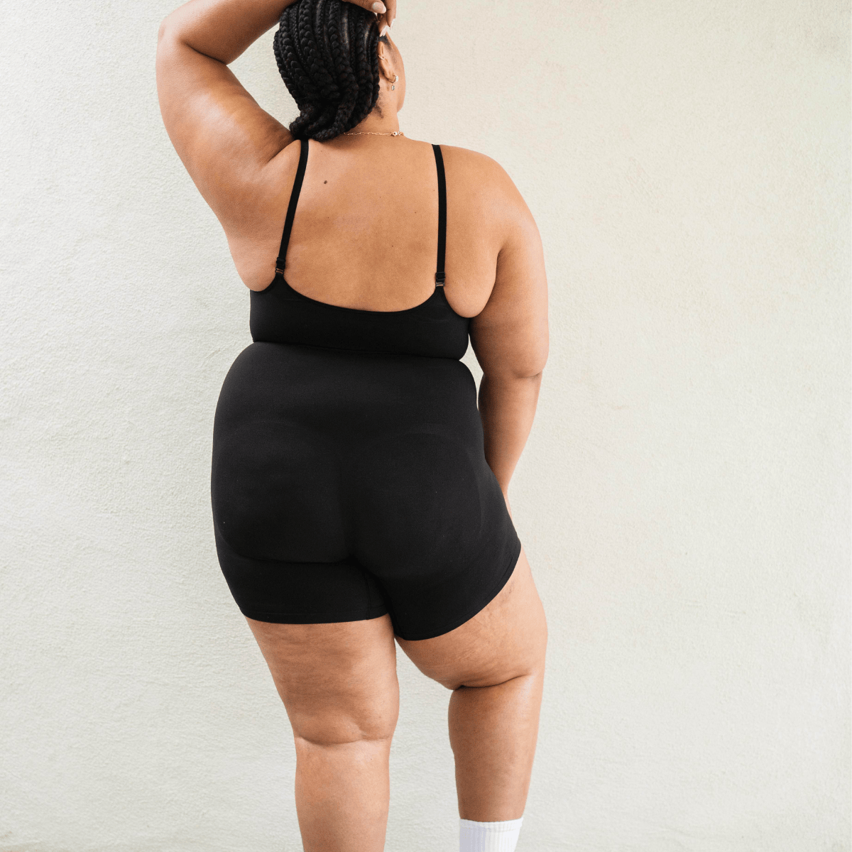 Back view of model wearing PROCLAIM Mid-Thigh Shapewear Bodysuit in Black
