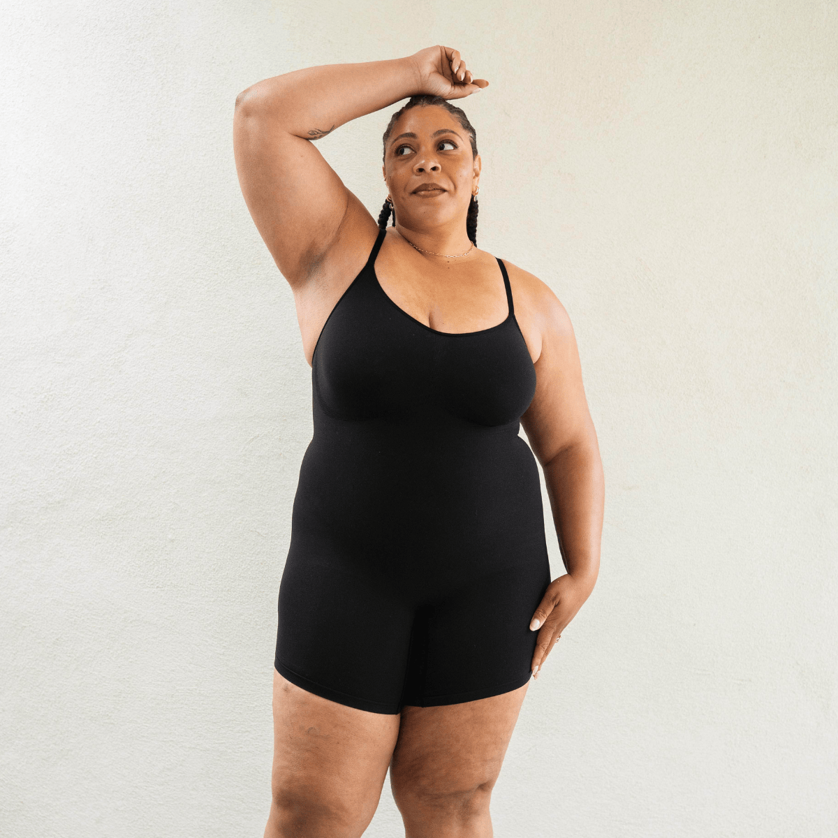 Model wearing PROCLAIM Mid-Thigh Shapewear Bodysuit in Black, front view