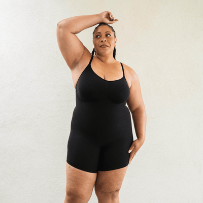 Model wearing black shapewear bodysuit with smoothing fit and breathable stretch