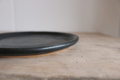 Black ceramic plate on a wooden surface with a neutral background