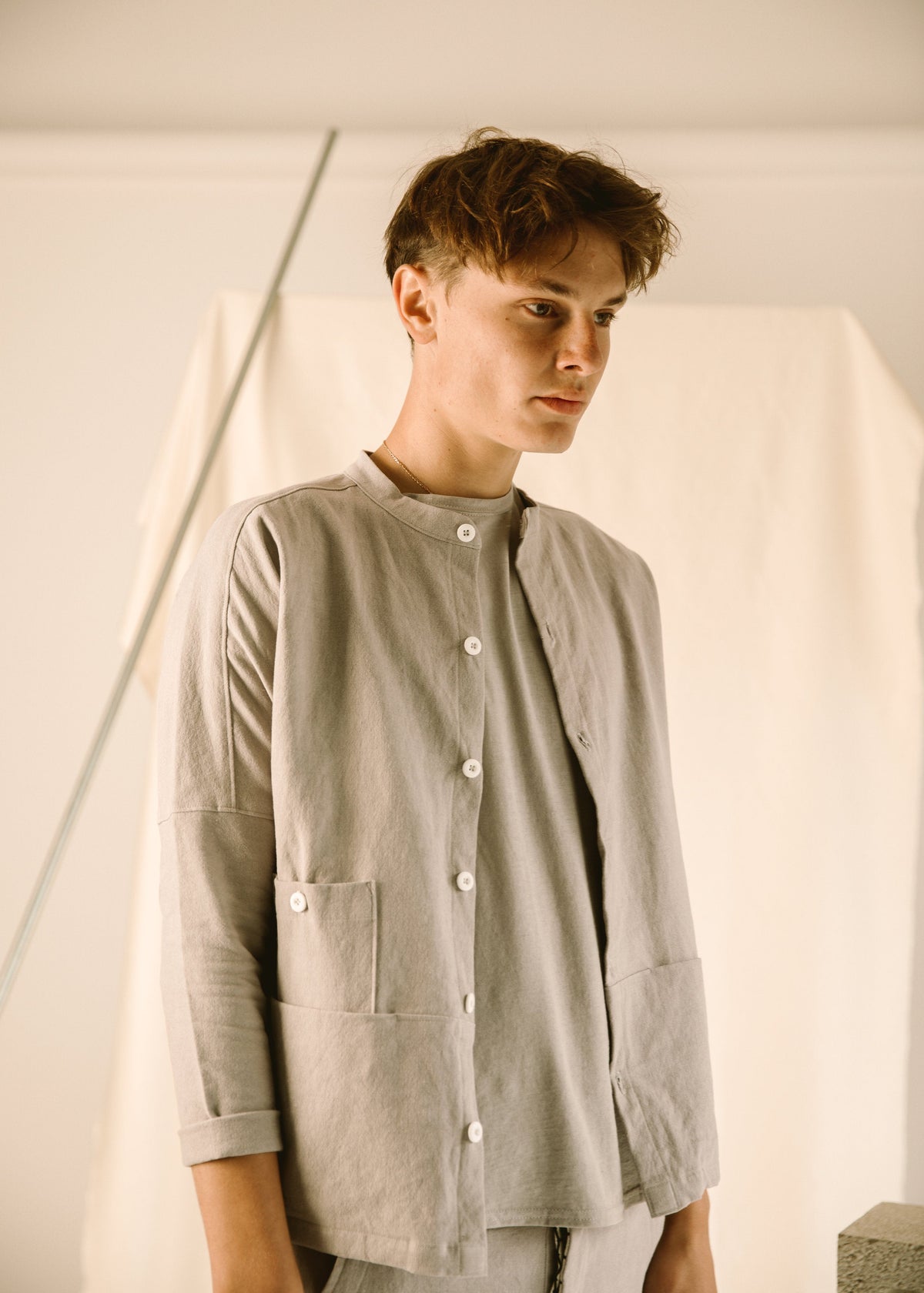 Three-quarter view of the light gray Raj coat showing its button front and patch pockets.