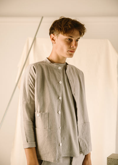 Three-quarter view of the light gray Raj coat showing its button front and patch pockets.