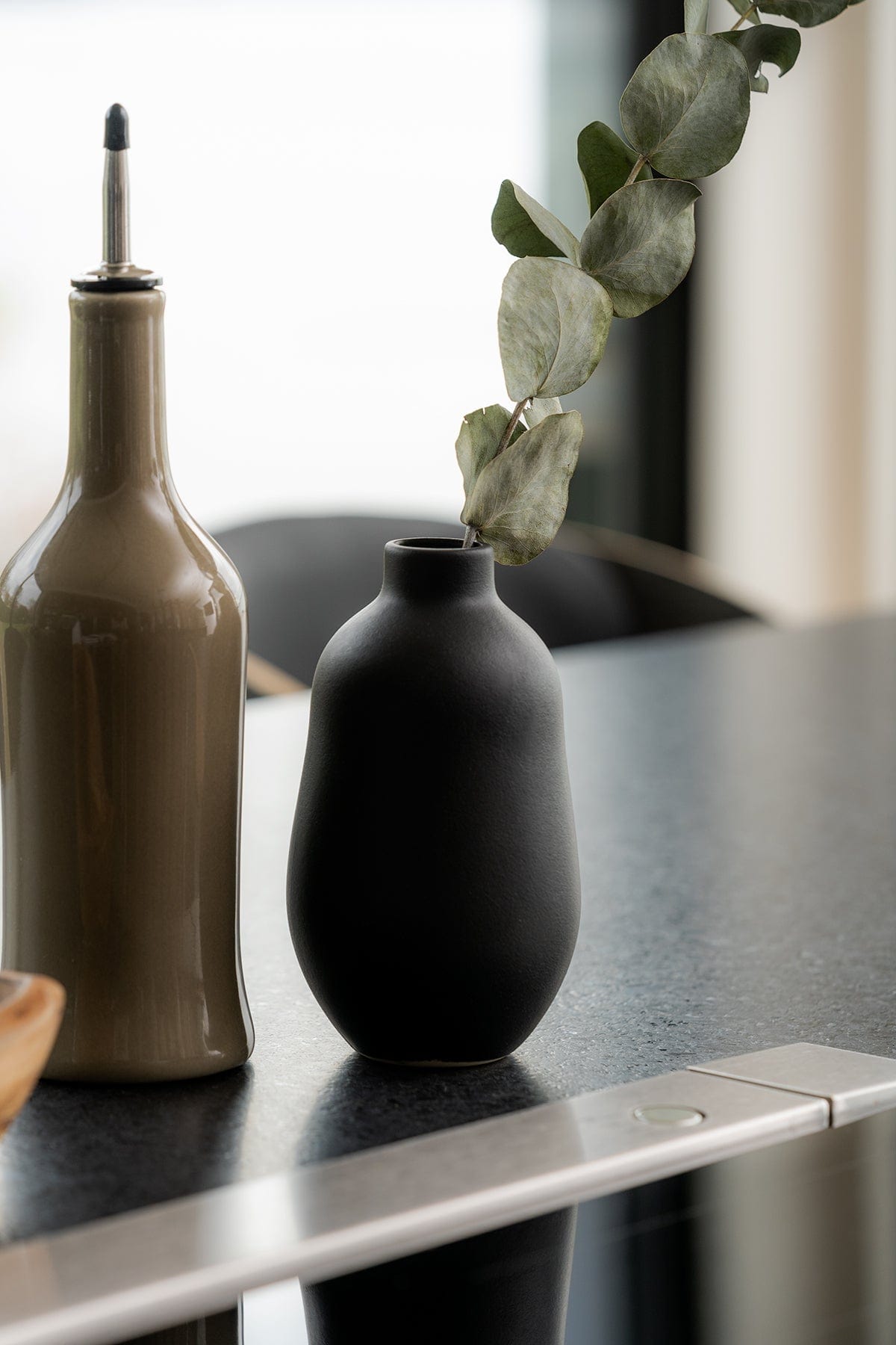 Gharyan Stoneware Vase, black, styled with oil bottle, eucalyptus