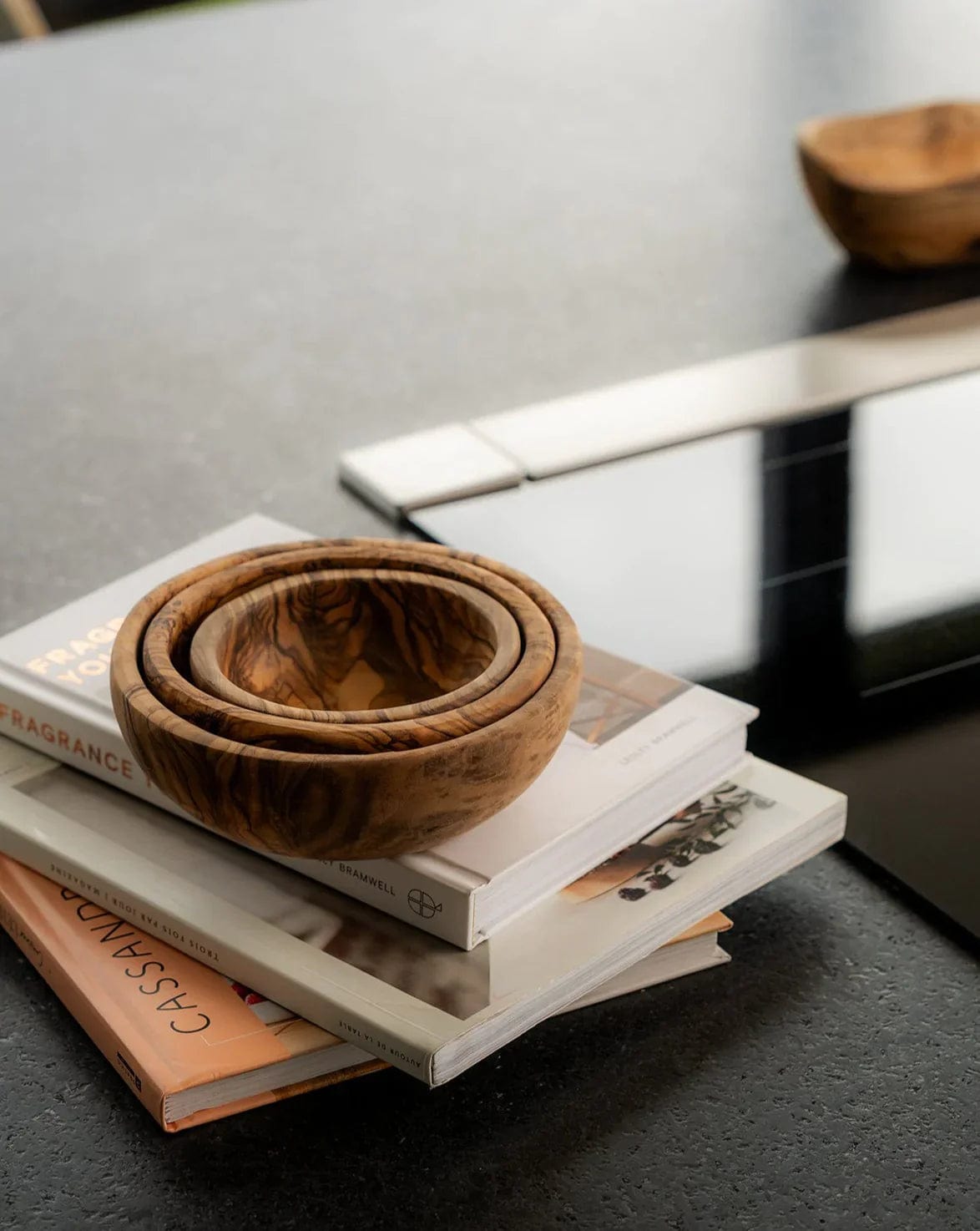 Gharyan Stoneware Olive Wood Nesting Bowls, set of 3, styled on stacked books