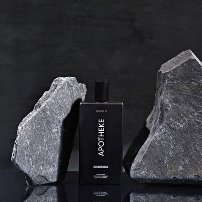 APOTHEKE Charcoal Room Spray bottle styled between two gray stone pillars on a dark surface