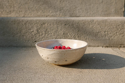 Ceramic Colander bowl with raspberries on a concrete surface