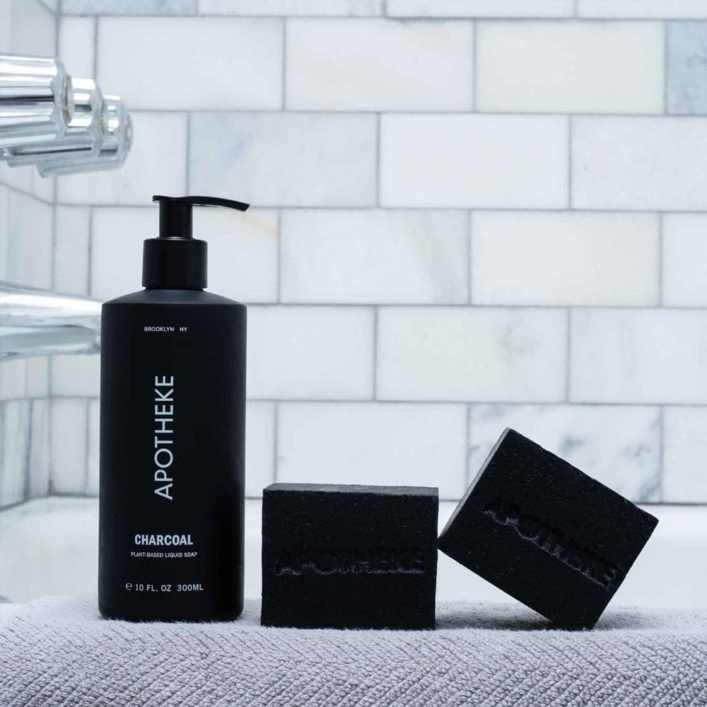 APOTHEKE Charcoal Liquid Soap bottle styled on a bathroom shower ledge with matching bar soap