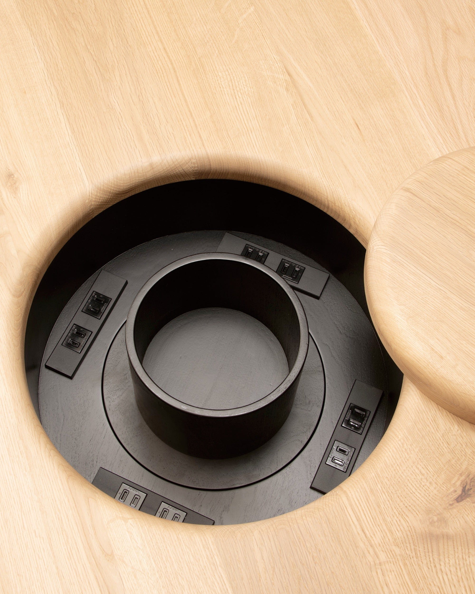 Close-up of built-in power module recessed into oak tabletop in ONE Round Table by CondeHouse