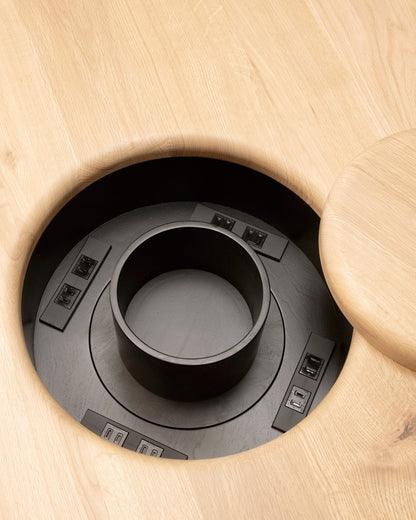 Close-up of built-in power module recessed into oak tabletop in ONE Round Table by CondeHouse