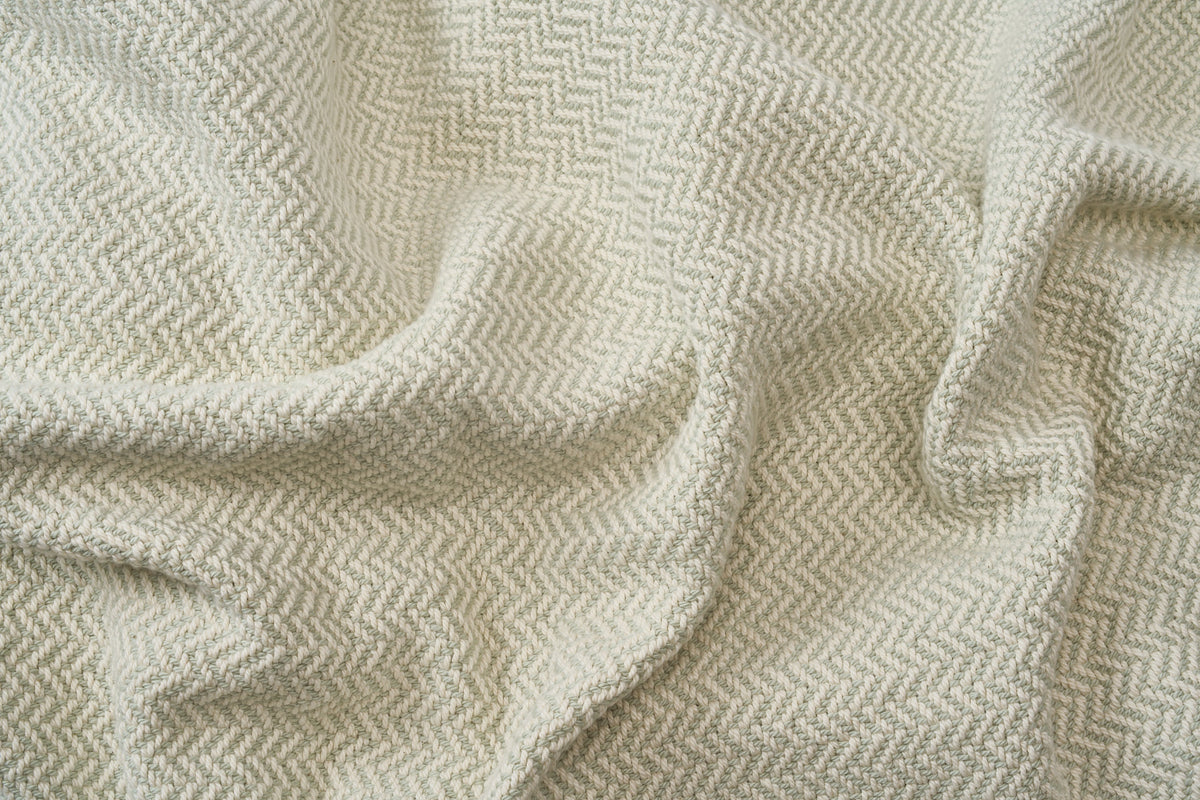 Close-up of textured light green fabric with a herringbone pattern