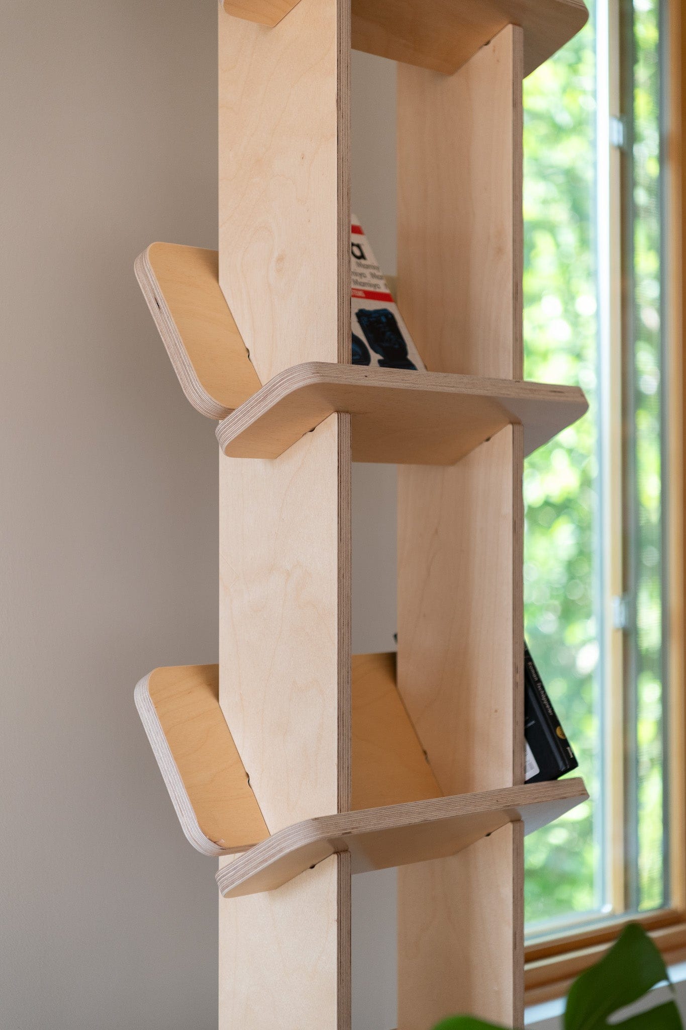 Close-up of the Yankel bookcase showing its central wood supports and upward-angled shelves designed to hold books securely