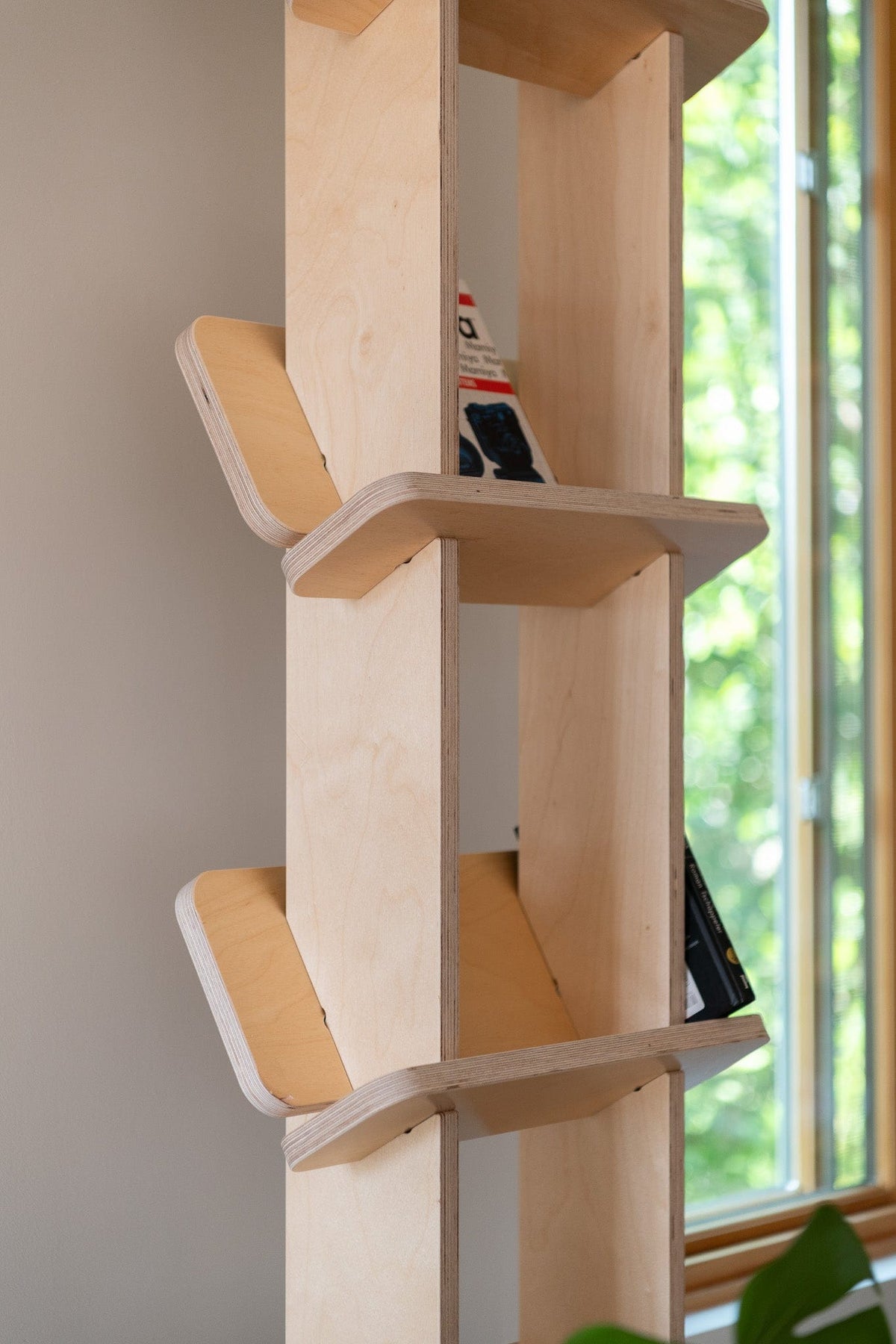 Close-up of the Yankel bookcase showing its central wood supports and upward-angled shelves designed to hold books securely