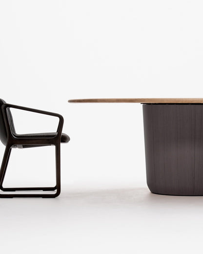 Detail view of ONE round dining table edge and central column base and EIGHT Armchair